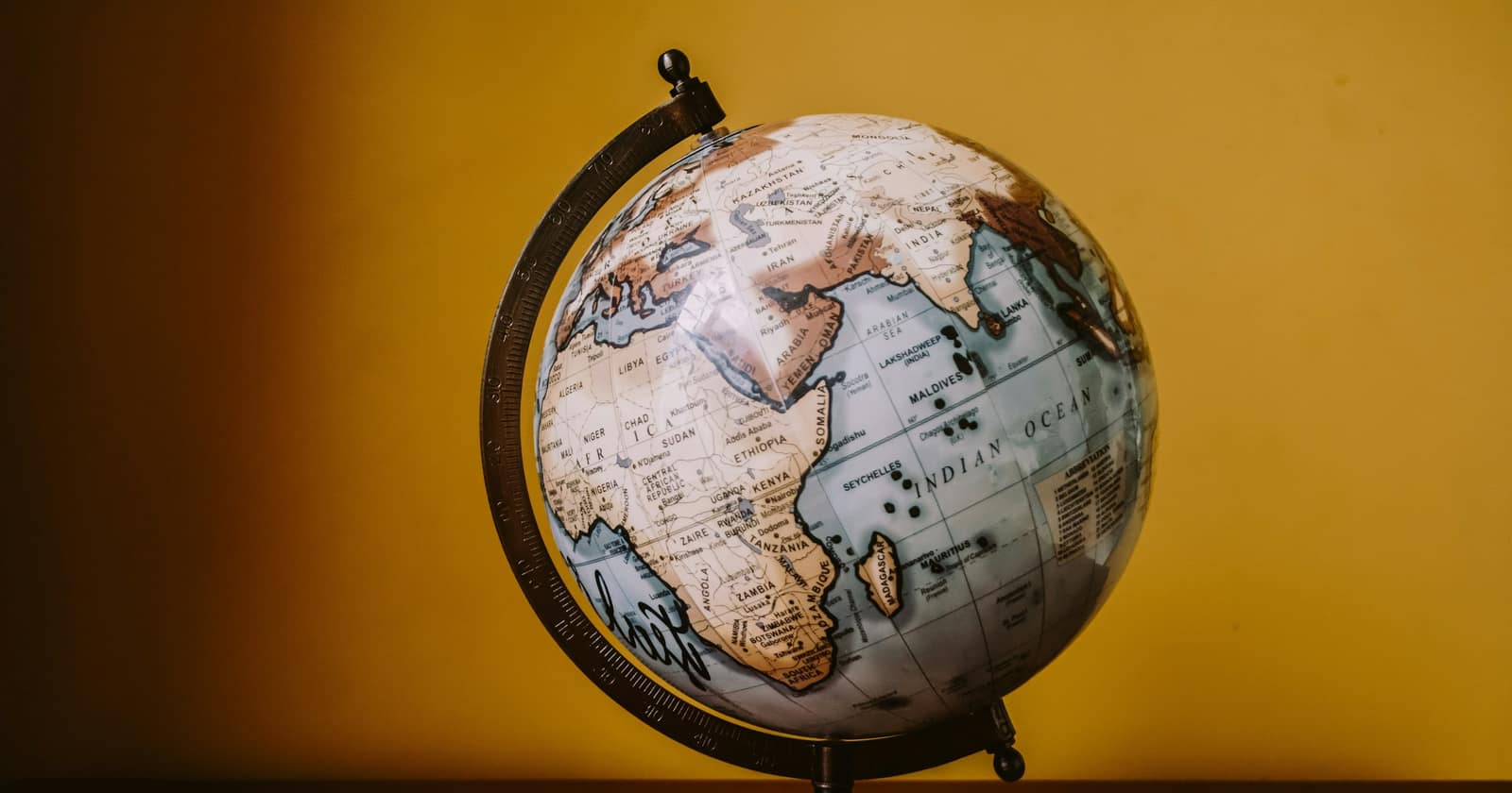 A small desk globe turned to Asia against a warm ochre wall