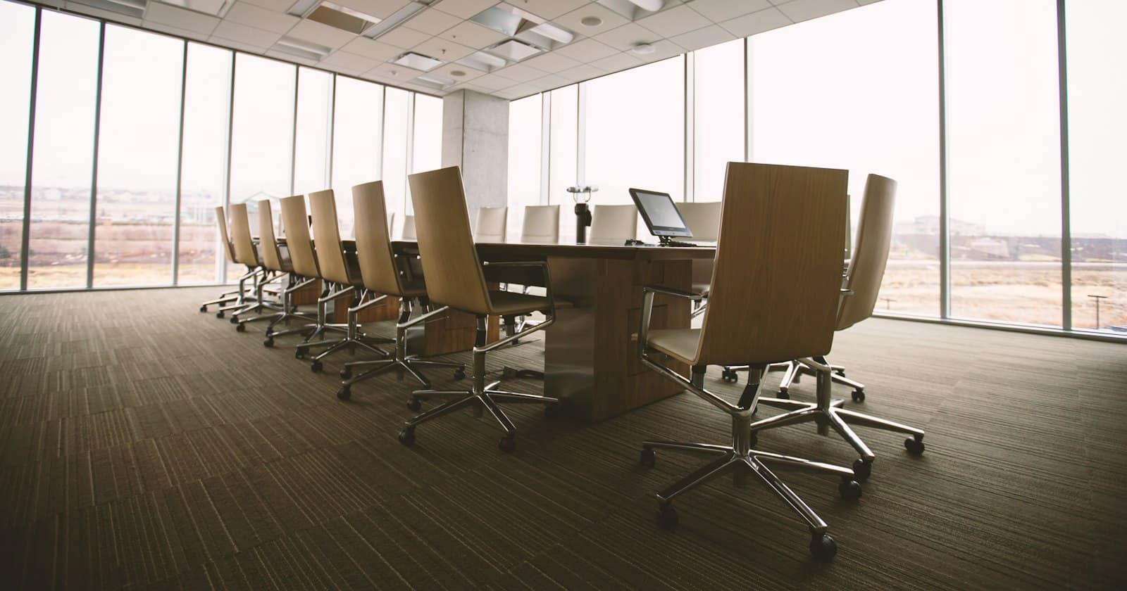 An empty boardroom with a long table and leather chairs