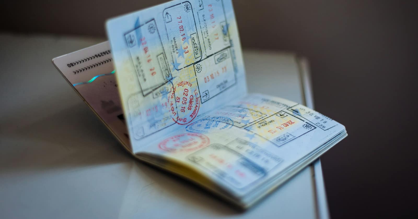 An open passport covered in immigration stamps, resting on a pale table
