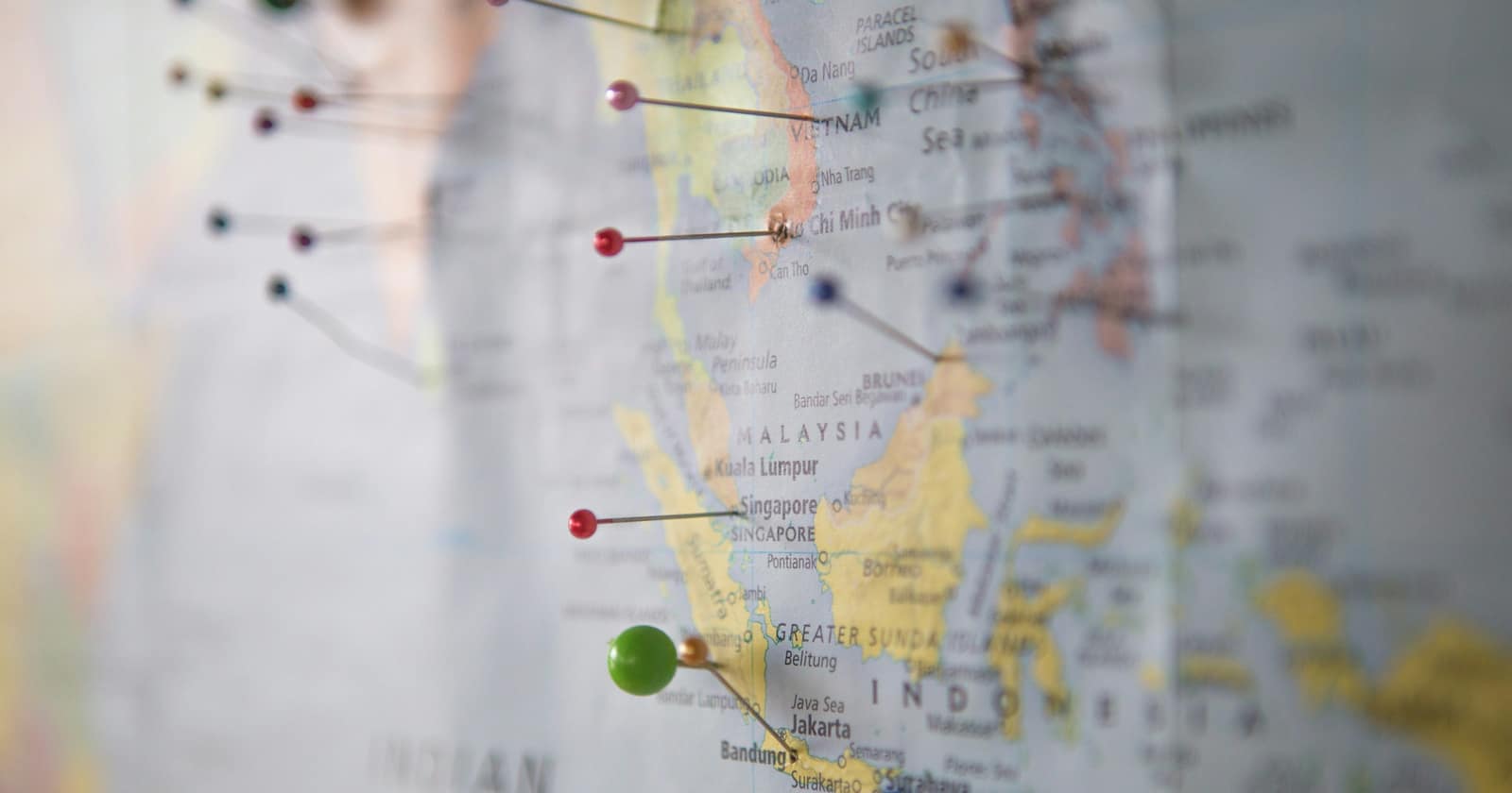 Coloured pins pressed into a world map across Singapore, Malaysia and Indonesia beside the Indian Ocean