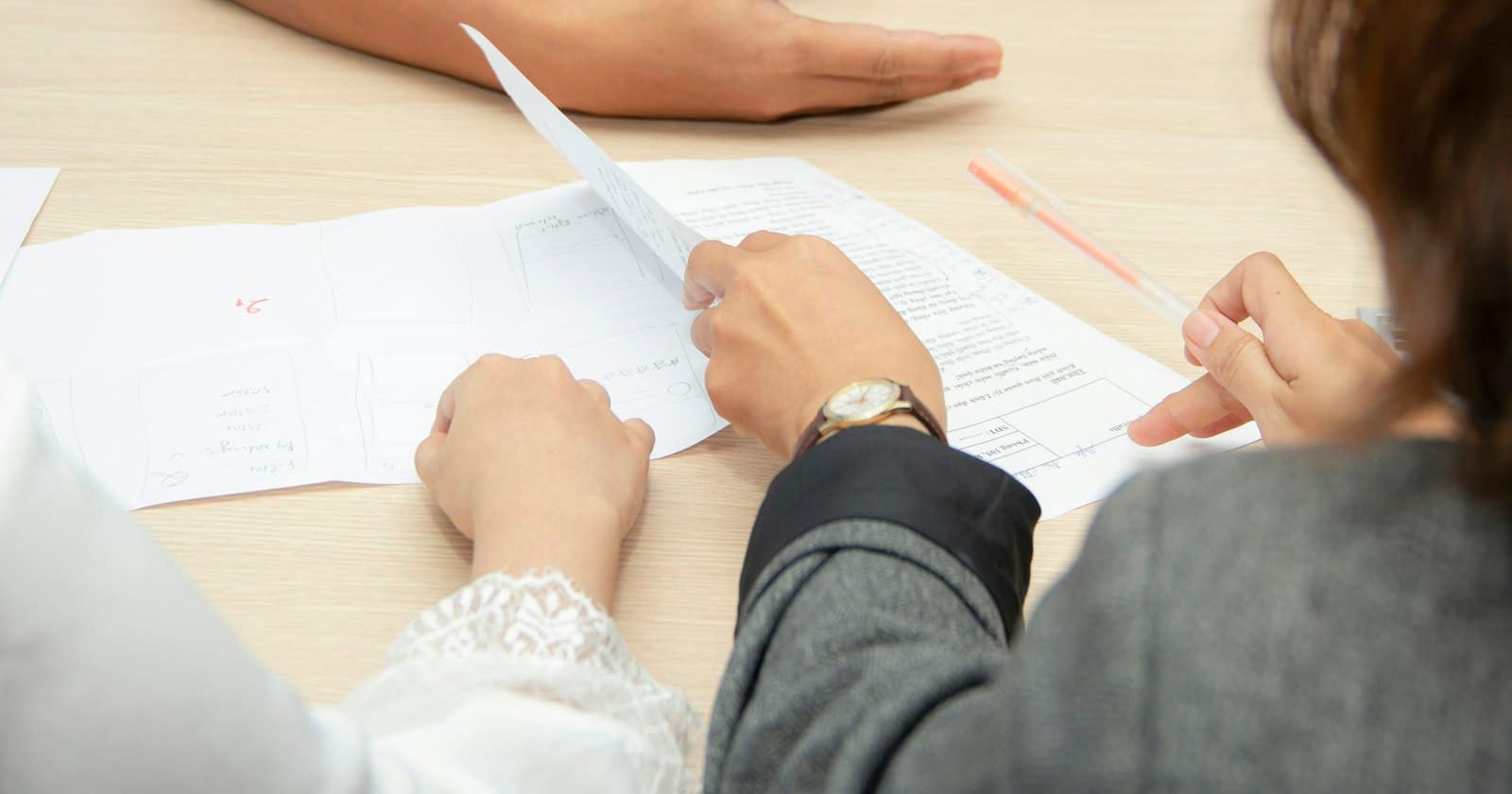 Two people going through printed documents together at a desk