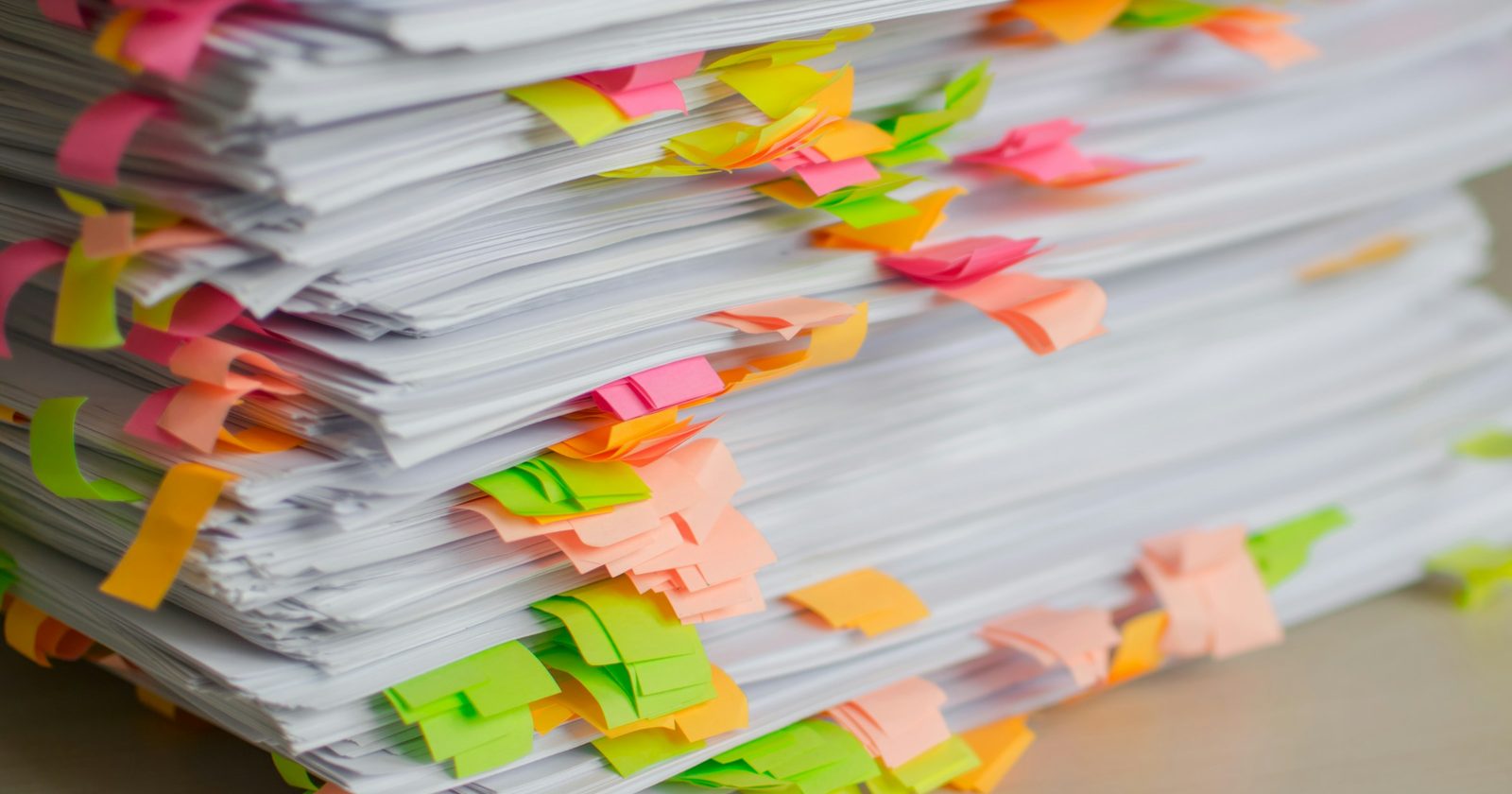 A thick stack of papers edged with coloured sticky tabs, each marking something that needs answering
