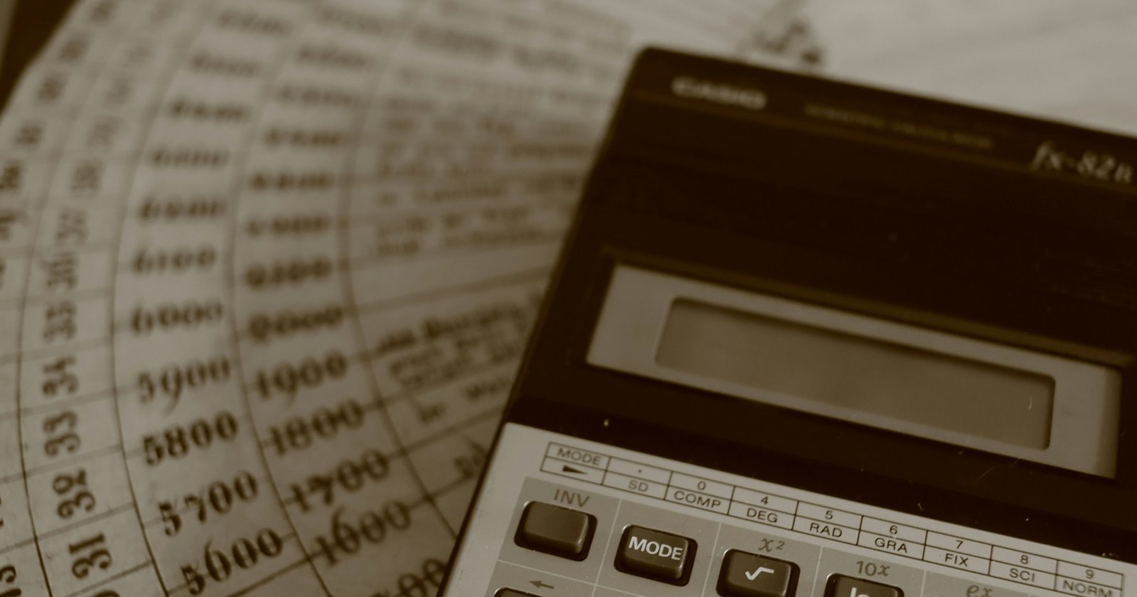 A calculator resting on old ledger sheets of printed figures