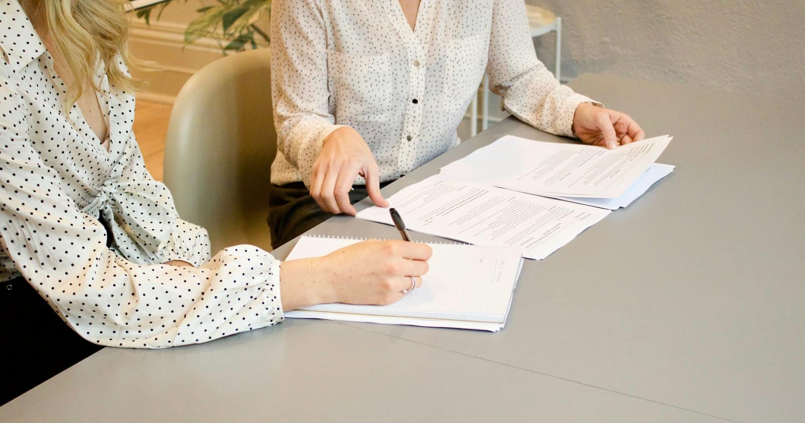 Two colleagues checking and signing printed documents at a table
