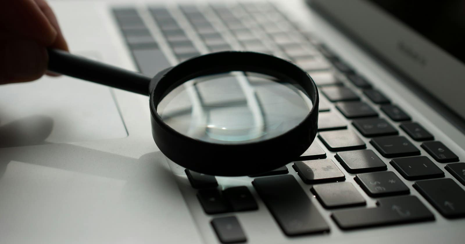 A magnifying glass held over a laptop keyboard