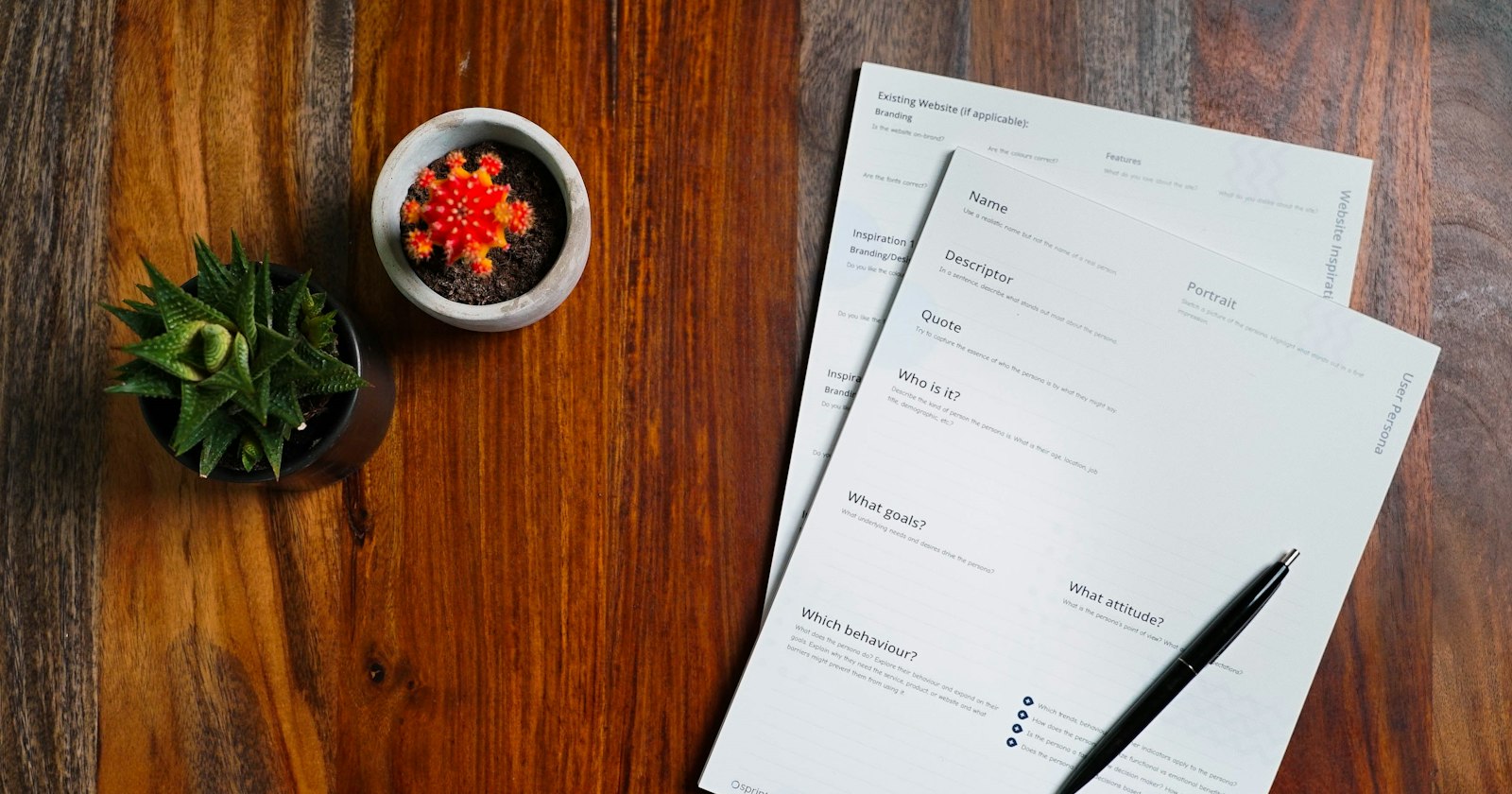Papers and a pen spread across a wooden table