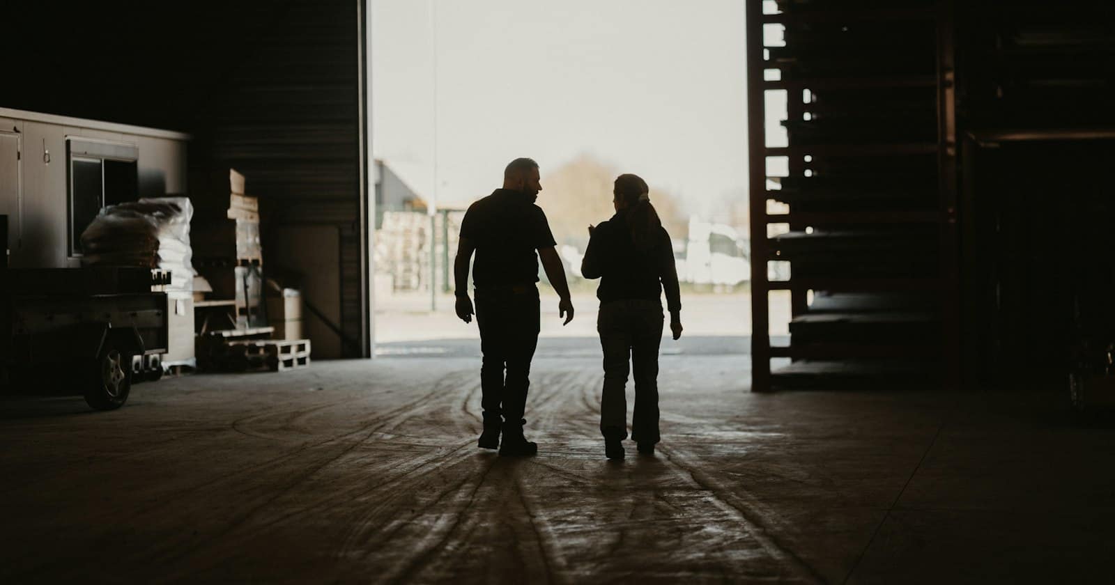 Two people walking together through the doorway of a warehouse