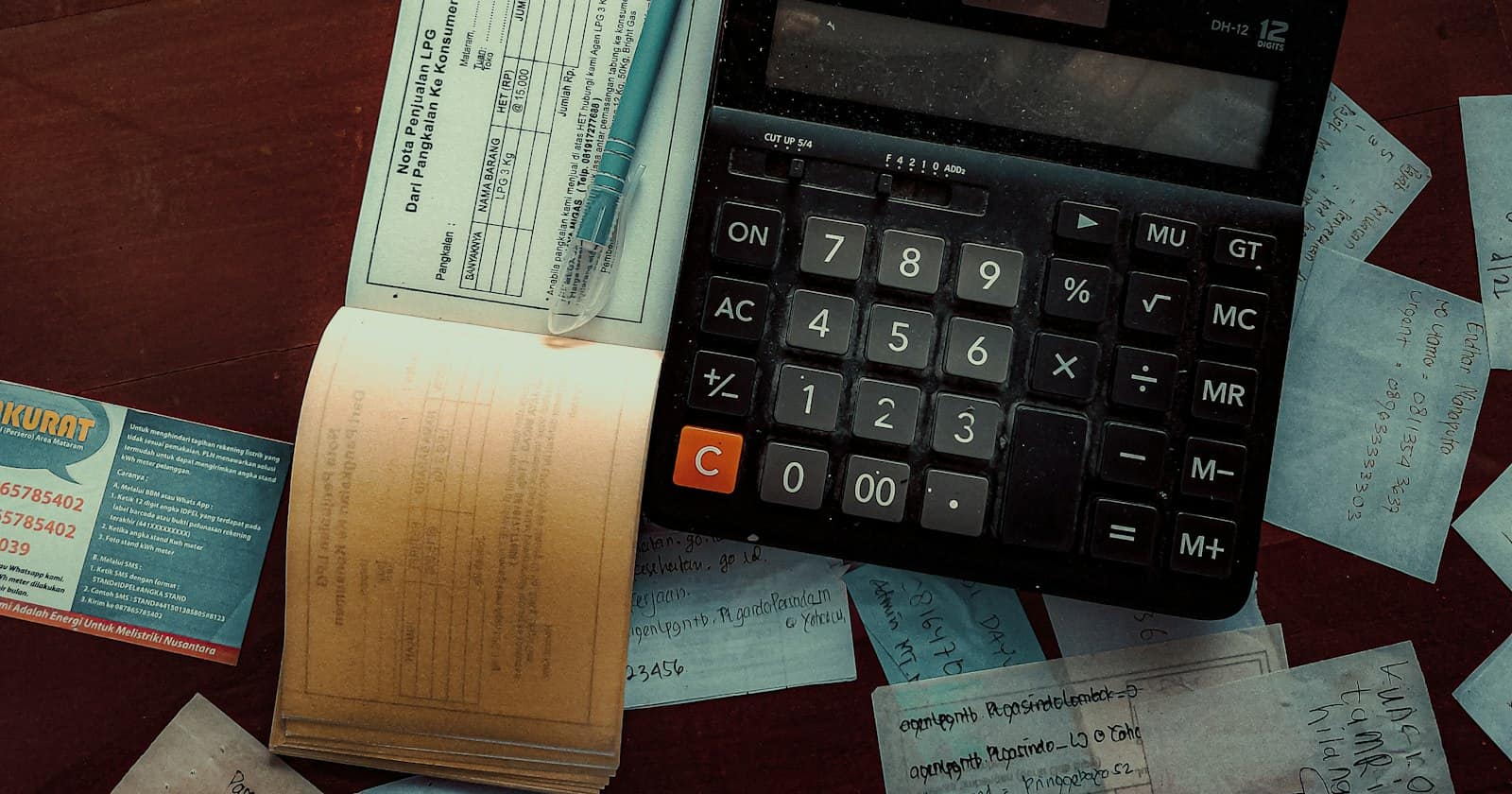 A calculator on a desk scattered with receipts and a counterfoil book