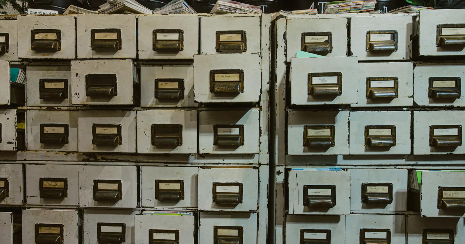Rows of old wooden filing-cabinet drawers, each with a handwritten label in its brass holder