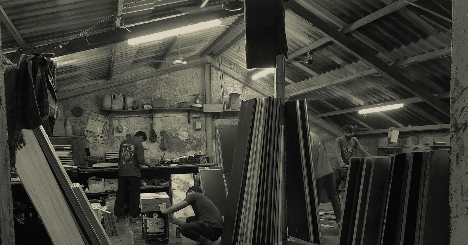 Workers in a small Indian workshop among stacked sheets of material