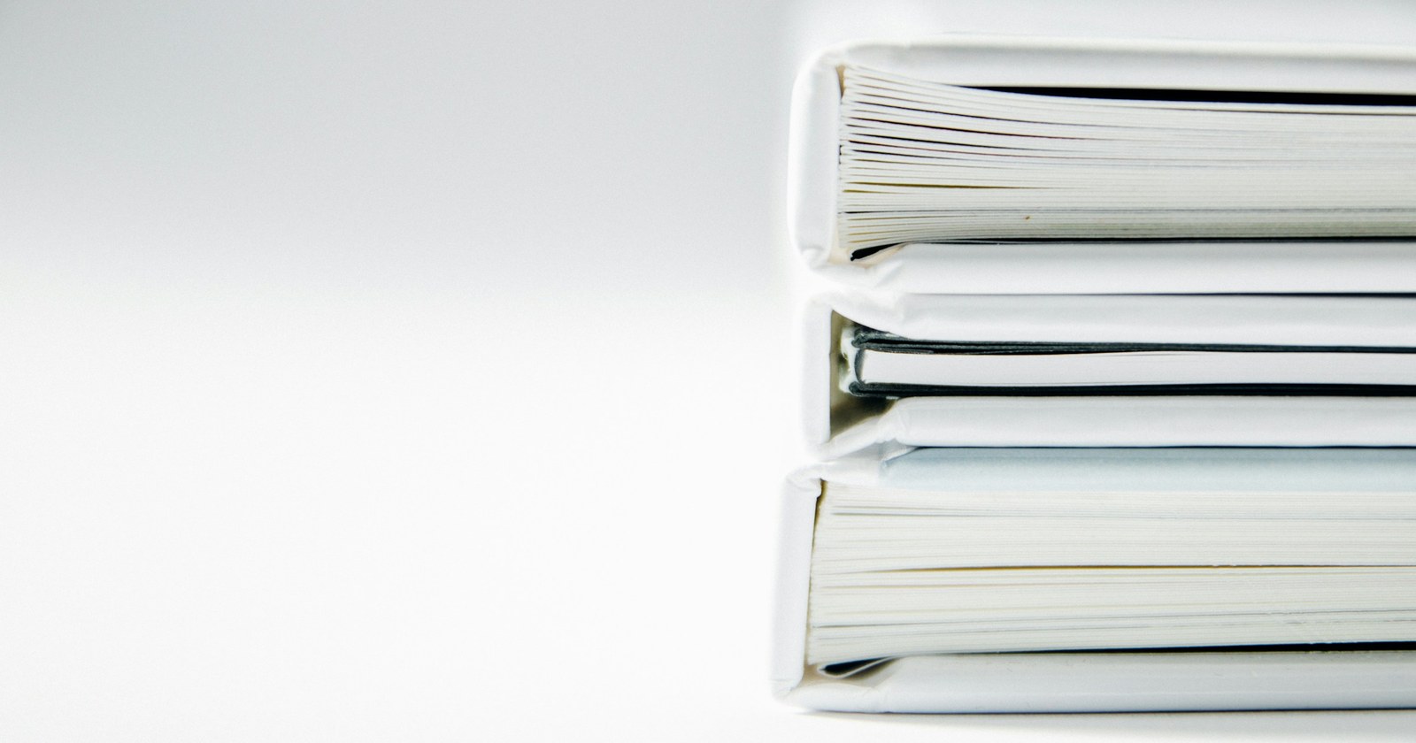 A stack of thick document folders on a white surface