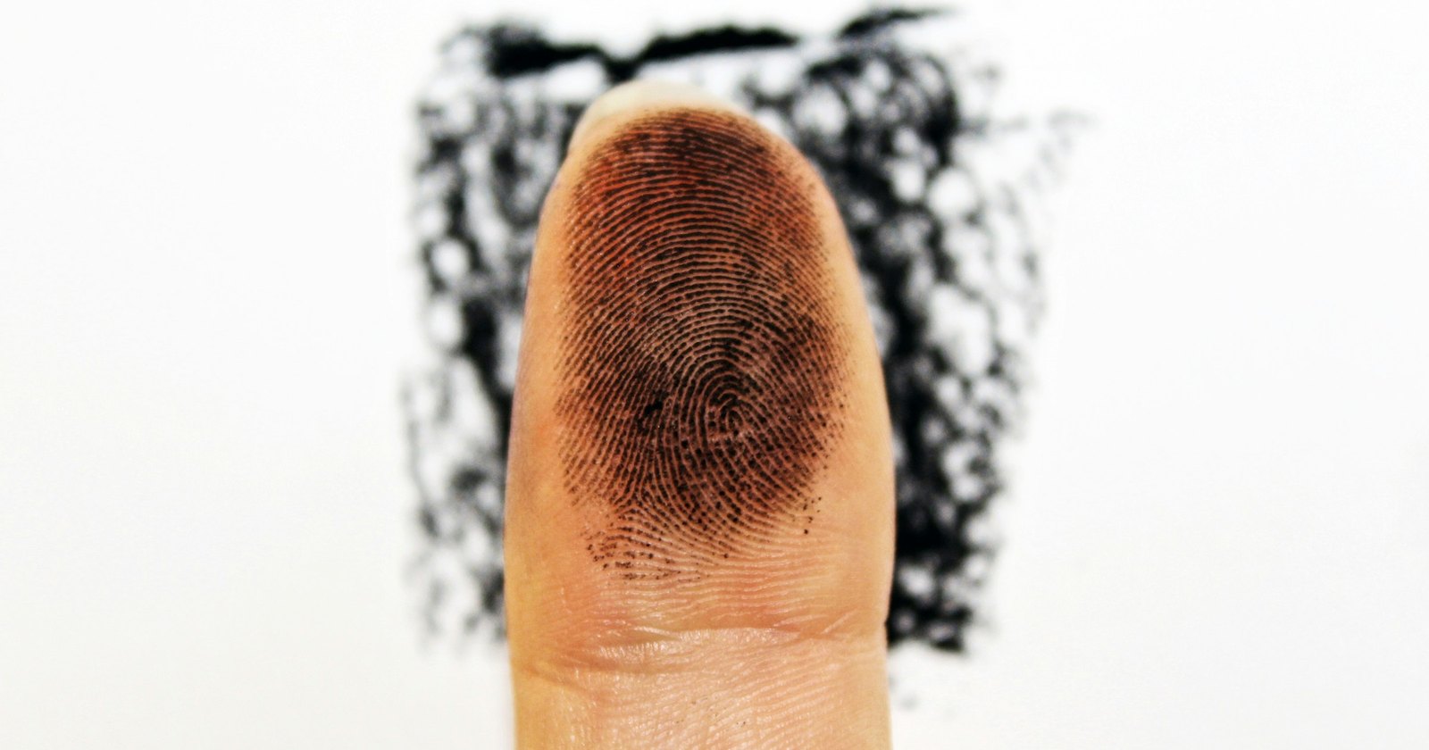 A fingertip pressed in black ink against a white background