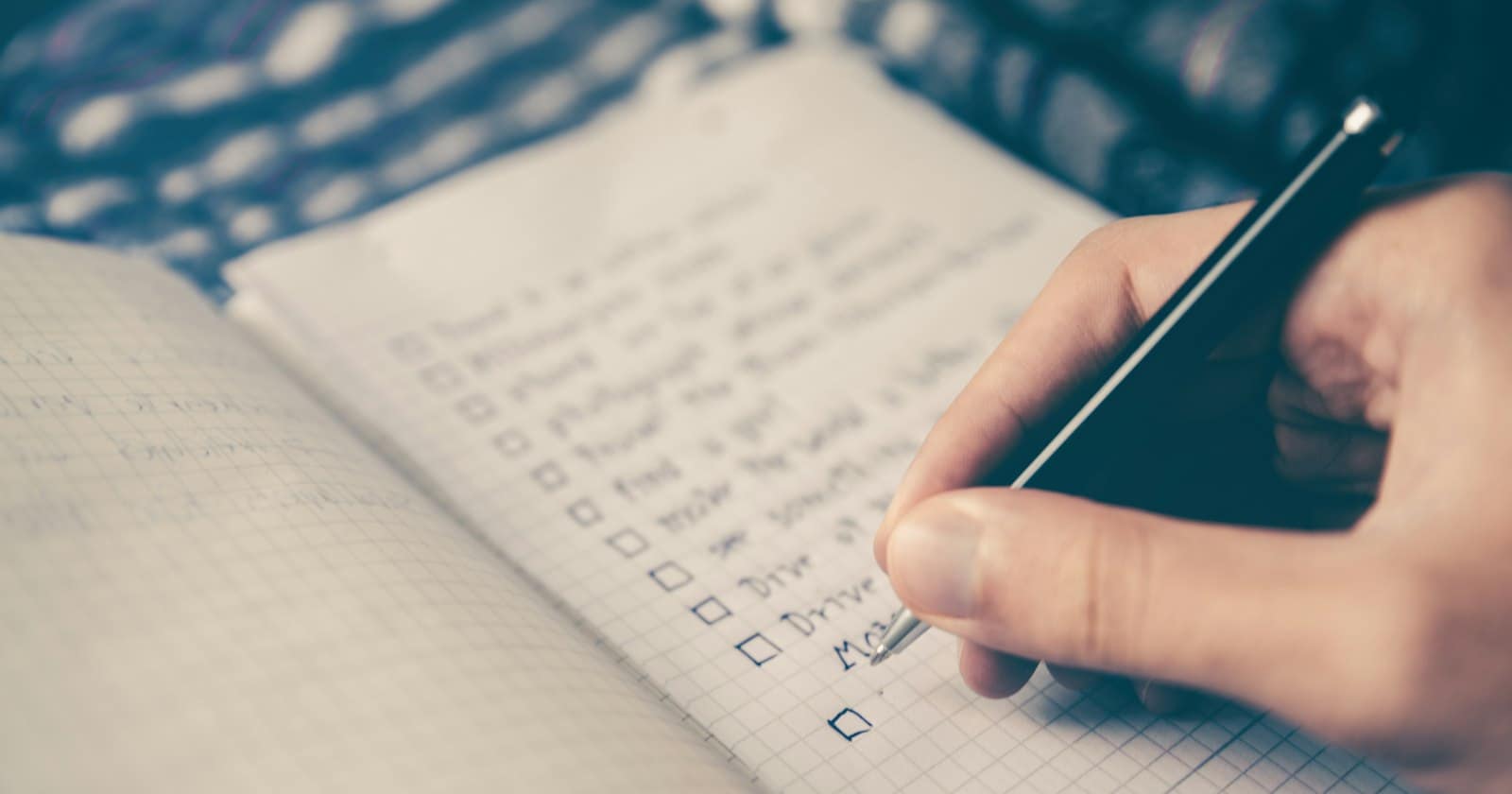 A hand ticking items off a handwritten checklist